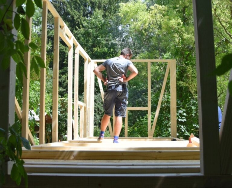 Handwerker auf einem Tiny House Trailer, während er ein Tiny House im Holzrahmenbau errichtet.